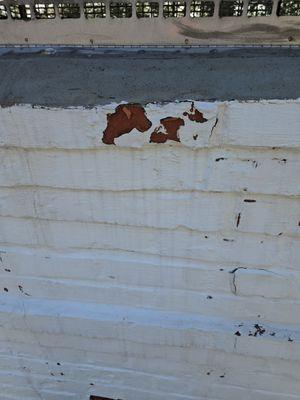 Deteriorating Drylok visibly separating from the brick face, exposing compromised masonry underneath