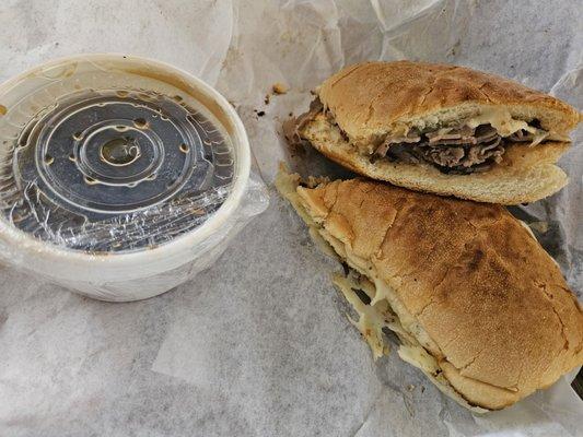 French dip with pepper jack and au jus wrapped in saran wrap for to go orders.