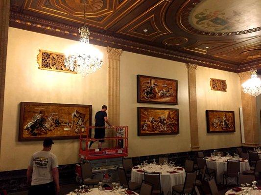 Installing a series of restored art that we custom framed for the Terrace at the Hotel Syracuse.