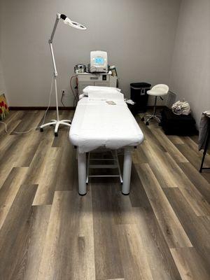 Treatment room with Xcell Epilator displayed , treatment table , magnification lamp , Technicians chair and environment supplies