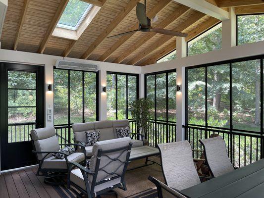 A custom 3-4 season room with sconce lighting, skylights, and horizontal track windows with screens Open rafter design with T&G ceiling.