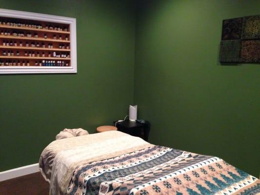 Massage room with therapeutic oils shelves and ultrasonic diffuser in view.
