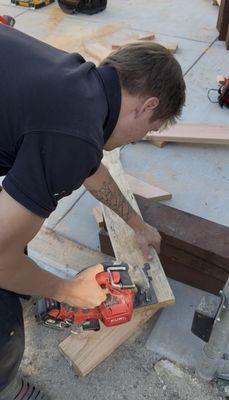 Custom cutting and fitting of wood beams for the carport frame.