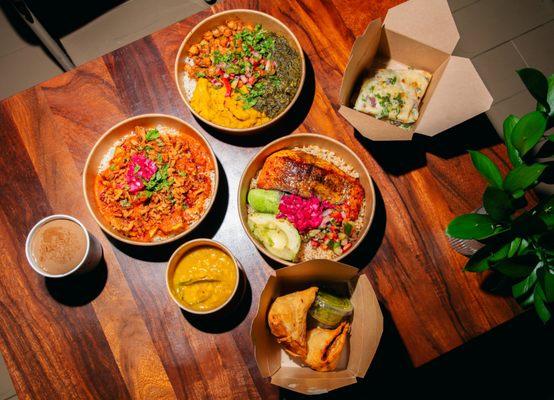 Table Spread, including Chicken Tikka Masala, Salmon Bowl, Samosas, Karma Bowl, & Daal