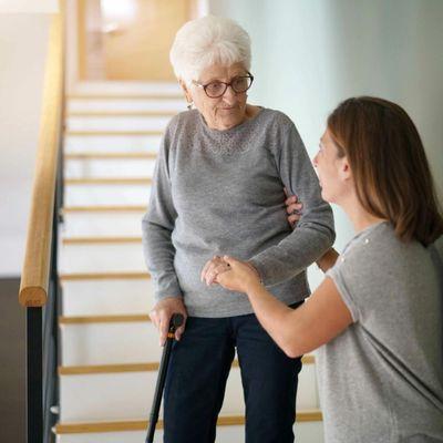 Lady assisting Elderly woman down stairs.