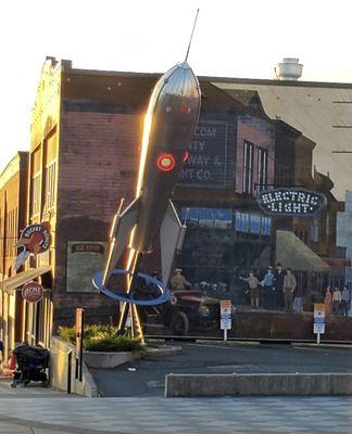The rocket sculpture is all lit up as dusk sets in.