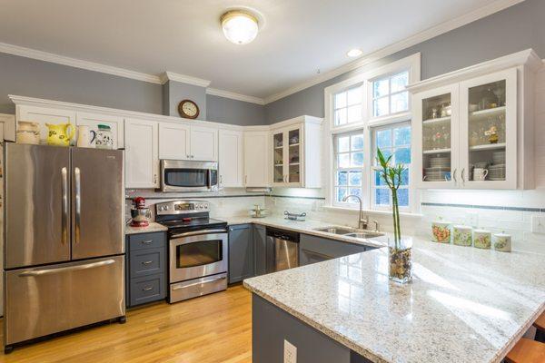 New cabinets, countertops, and tile backsplash with an accent strip.