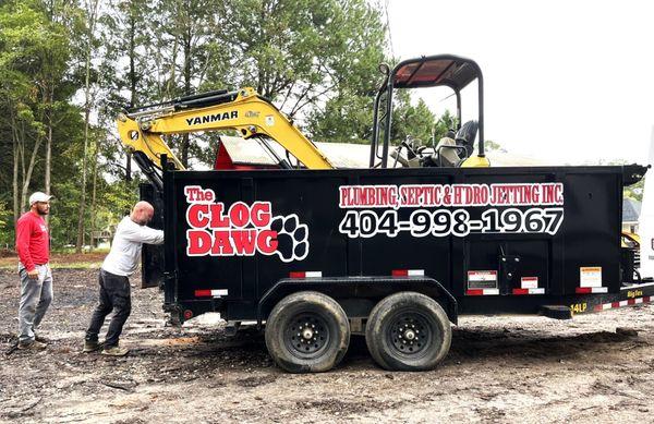 Technicians loading excavator into work trailer