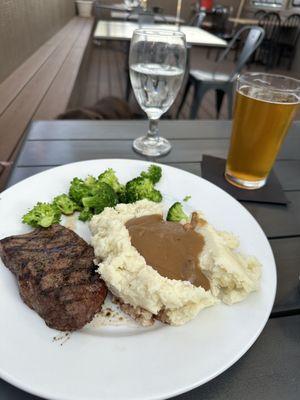 Flat iron steak with mashed potatoes, gravy, broccoli sides.