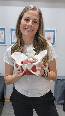 Smiling Physical Therapist in clinic holding a Pelvis