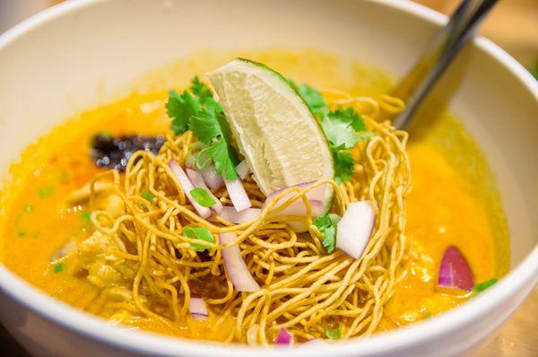 Khao Soy Noodle: Egg noodle with chicken, green onion, red shallot cilantro in northern Thai style yellow curry topped with crispy noodle.