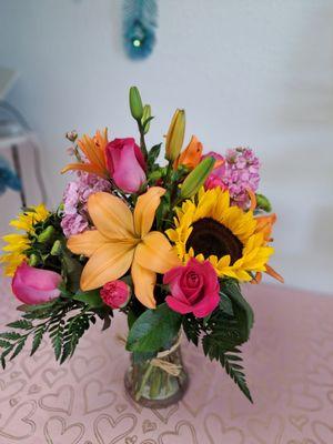 This beautiful, colorful sunflower and pink roses orange lily's in a clear cylinder for a birthday or just because.