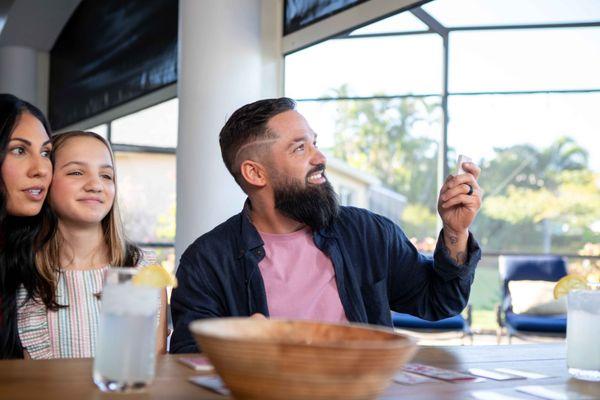 A Florida homeowner demonstrates the ease of operating Smart View impact windows and doors while his family enjoys the comfor...