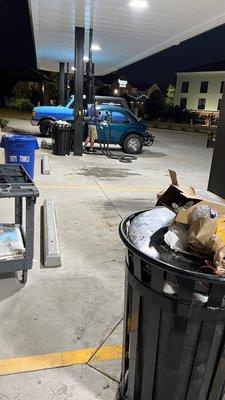Worker cleaning his own car instead of getting rags done or emptying overloaded trash cans.