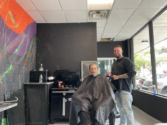 At the beginning of cut/ shave Cool backsplash on wall painted by Justin the Barber-