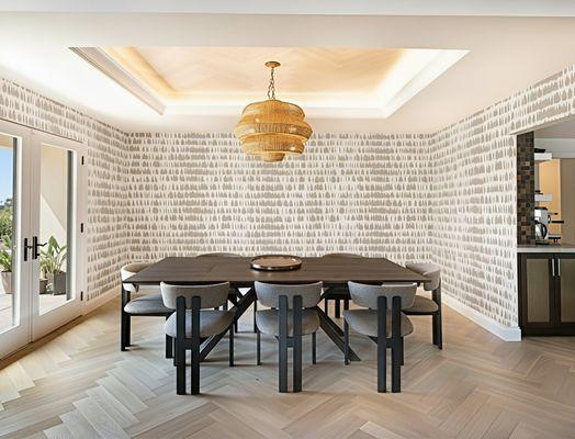 Modern formal dining room with beautiful wallpaper, herringbone floors, lighted wood inlay ceiling and large wicker chandelier