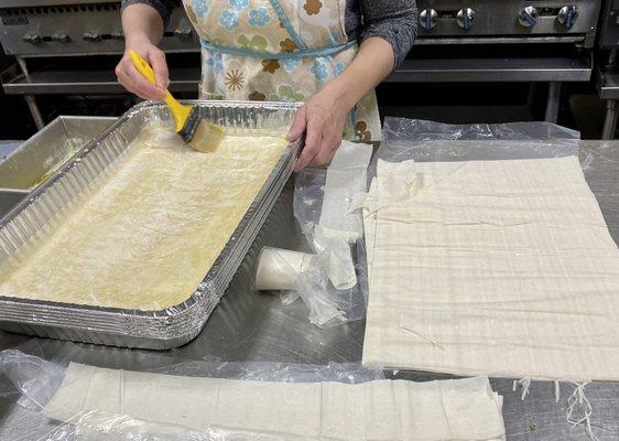 My friend layering and buttering the phyllo dough