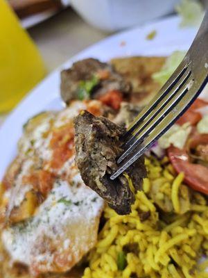 A fork with a piece of lamb meat.