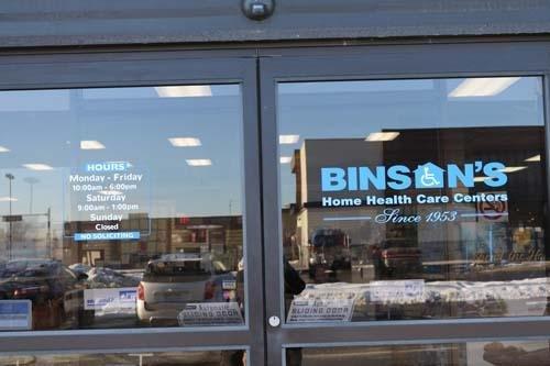 Close-up of the automatic entrance doors at Binson's Flint, showing the store hours posted on the left and the Binson's Home ...