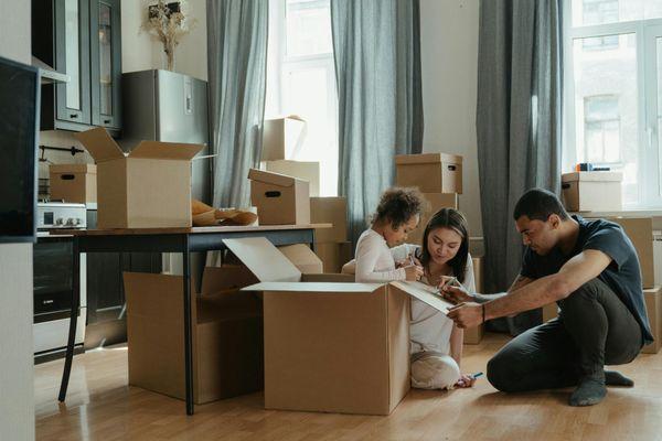 Family moving and unpacking boxes in kitchen.