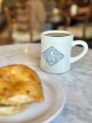 Sausage, egg and cheese on a cheddar bagel with a drip coffee