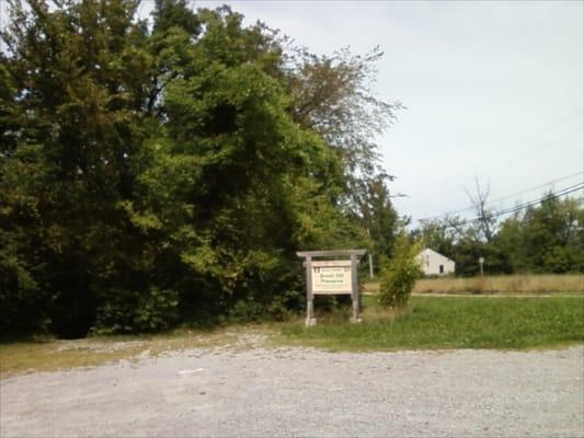 Gravel lot (empty--you can enjoy the preserve in seclusion) and sign, viewed from Fire Dept. side.