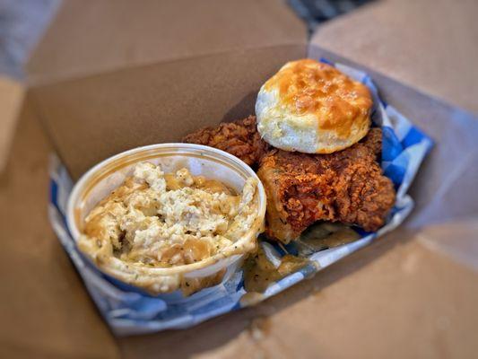 Two piece meal with thigh and leg with a side of Mashed potatoes and a biscuit.