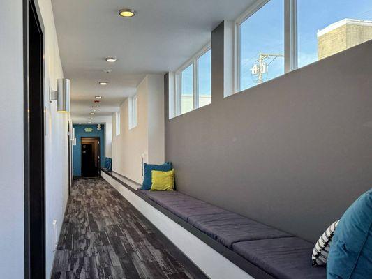 A long hallway with a bench and a door at the end.