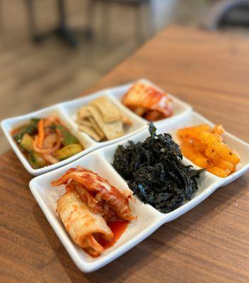 Complimentary Banchan - Kimchi, cucumber kimchi, fish cakes, pickled radish, and seaweed flakes
