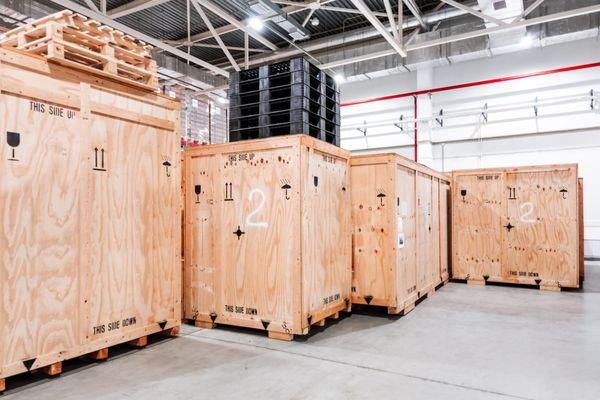 Four large custom wooden crates delivered and staged in a client's warehouse. Built for heavy-duty shipping and storage, precision-crafted
