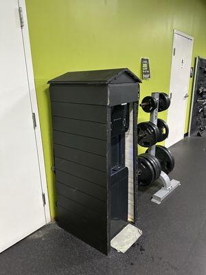 Same water station from a different angle -- cooler is inside a rough wooden frame with a tank on the side.