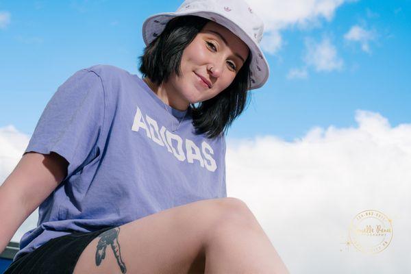 bright and happy creative portrait of a young woman in a casual outfit against a bright blue sky