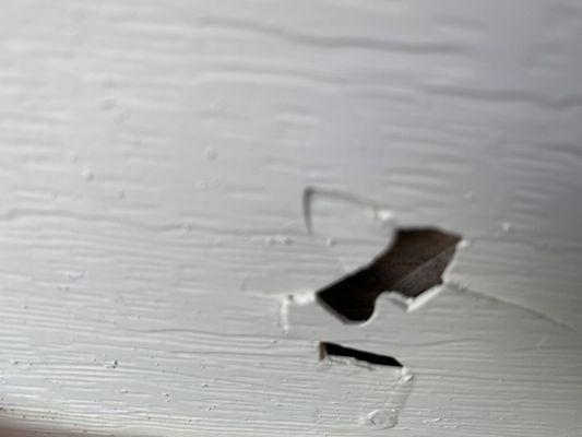 Damaged siding they tried to cover by stacking mulch in front of this.