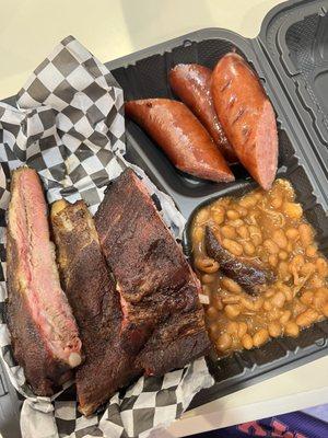 Rib platter with sausage and baked beans as sides.