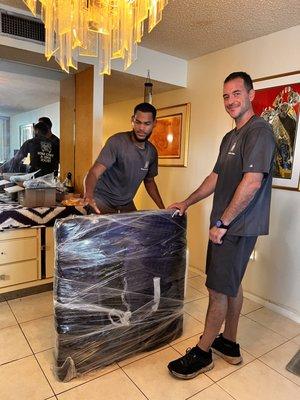 Carefully packing, taping, carrying items. Eliot and Jorge
