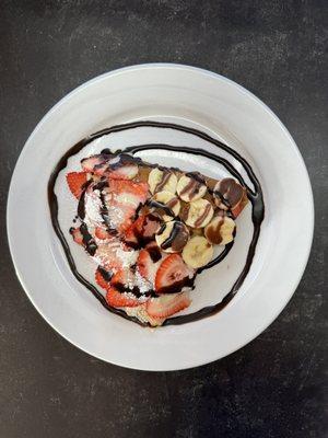Crepes with banana and strawberry topped with powdered sugar