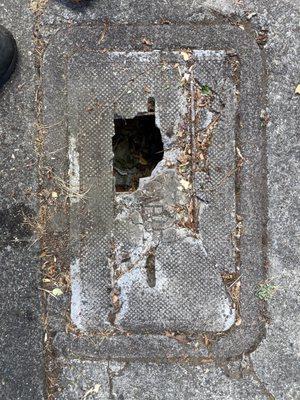 The broken concrete lid on sidewalk