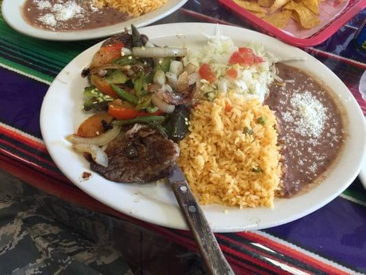 Steak platter topped w/ onions,bell peppers. Tomato, lettuce, rice, and beans.