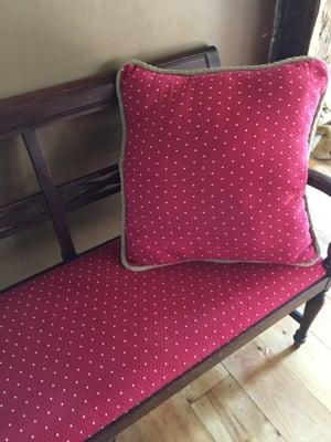 Reupholstered antique bench with oversized fun throw pillow done in quilted red soft fabric.