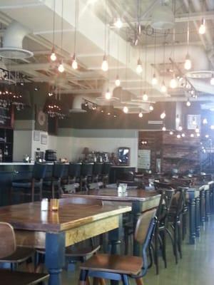 Main dining area lit uo by edison bulbs. They have a whole wall of refrigerated beverages, and specialty beers.