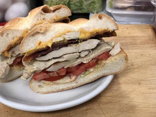 Chicken bacon melt on a Kaiser roll shaved lettuce tomato and mayo bacon and America cheese