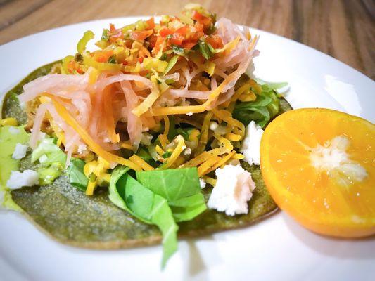 Mango BBQ jackfruit tacos with a plantain/spinach/moringa tortilla, eggplant & corn salsa, lettuce, pickles & coconut cotija cheese