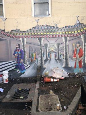 Mural on lower part of building next to parking spaces..