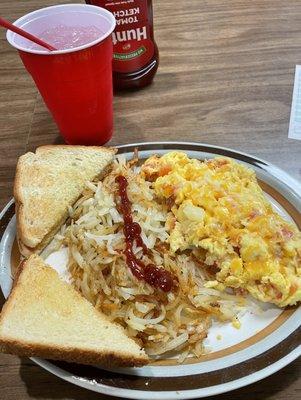 Scrambled eggs with cheese, onions, and tomatoes, hash browns, and buttered toast.