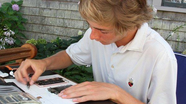 Sister company Nantucket iPhone Repair's owner, Grayson Shaw, repairing a phone.