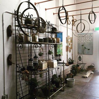 Garden Section with hanging iron mobiles, garden tools, grow kits, terrariums, and plants.