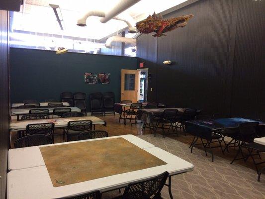 Huge room that l assume is used for Magic the Gathering events. The store sells MtG packs as well as single cards.