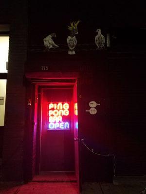 Look for a recessed door that's emitting red and blue light onto the street...